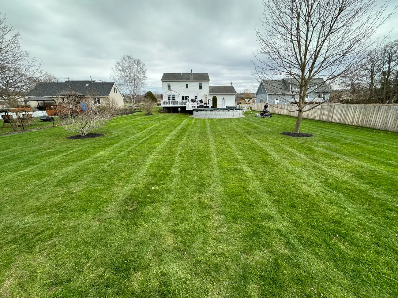 Professional lawn mowing and edging service on a residential property near Conesus Lake